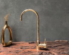 a gold faucet sitting on top of a wooden table next to a vase