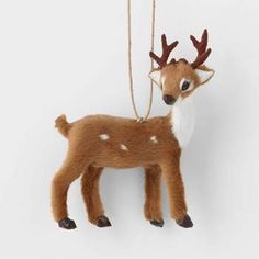 a small deer ornament hanging from a string on a white wall with no background