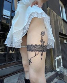 a woman's thigh with a cross tattoo on her lower leg and black lace