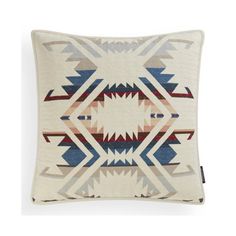 a white pillow with blue, red and grey geometric designs on the front is shown