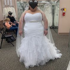 a woman in a white wedding dress standing in front of a mirror with her veil over her face