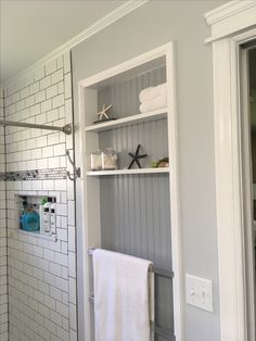 a bathroom with a shower, towel rack and white towels on the shelf next to it