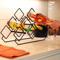 a person pours wine into a glass in front of a rack with bottles and glasses