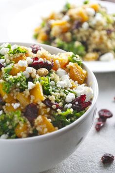 two white bowls filled with food sitting on top of a table next to cranberries