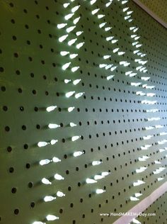 the perfored wall has holes on it and is lit by sunlight coming through