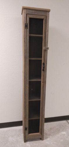 a tall wooden book case sitting on top of a white floor next to a wall