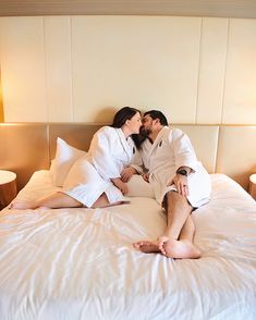 a man and woman in white robes laying on a bed