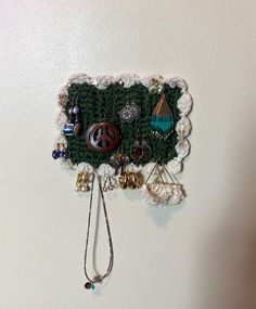 there is a green crocheted wall hanging with beads and other things on it