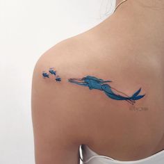 the back of a woman's shoulder with a blue bird tattoo on her left arm