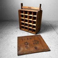 an old wooden box with chinese writing on it next to a small square shaped object