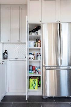 a stainless steel refrigerator and freezer combo in a white kitchen with black tile flooring