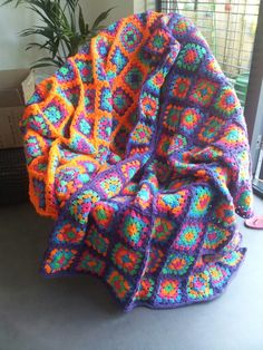 a crocheted blanket sitting on top of a table next to a potted plant