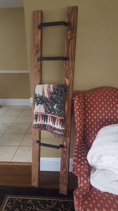 a ladder leaning against the wall next to a chair with a towel on it,