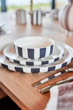 black and white striped plates sitting on top of a wooden table next to utensils