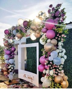 an arch decorated with balloons, flowers and greenery for a birthday party or wedding