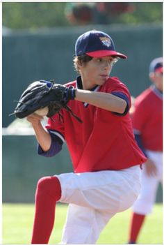 a young boy pitching a baseball on top of a field