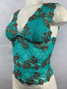 "Hand decorated sleeveless lace top in Green and Copper Gold color combination on floral patterned lace with shiny sequins and beads. Perfect for any occasion. 1. Available in 4 sizes: S, M, L, and XL. 2. Has three rows of hooks-eye position at the back which makes it easy to fit perfectly in your body. 3. Made from stretch lace which helps you easily adjust to your body size. 4. Individually hand beaded. 5. Light in weight and comfortable to wear. 6. Has cotton lining in the inner bust area to Green And Copper, Crop Top Sleeveless, Gold Color Combination, Lace Sleeveless Top, Sequin Crop Top, Long Crop Top, Top Sleeveless, Stretch Lace, Body Size