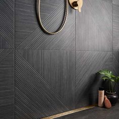 a bathroom with black tiles and gold fixtures on the wall, including a shower head