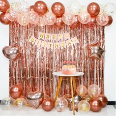 a birthday party with balloons, streamers and a cake on a table in front of a backdrop