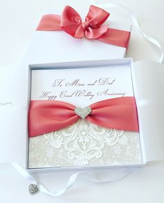 a wedding card in a box with a red bow on the front and white back