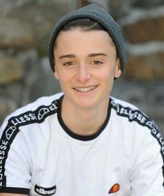 a young man wearing a beanie smiles at the camera