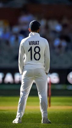 a man standing on top of a lush green field next to a cricket ball and bat