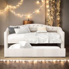 a white daybed with pillows and blankets on it in front of a christmas tree