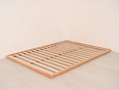 a wooden bed frame sitting on top of a hard wood floor in an empty room