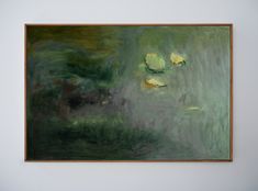 a painting hanging on the wall in front of a white wall with green and yellow colors