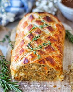 a loaf of meatloaf sitting on top of a cutting board next to some herbs