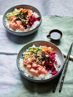 two bowls filled with rice and vegetables next to chopsticks