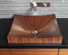 a wooden sink in front of a brick wall and black counter top with stainless steel faucet