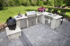 an outdoor kitchen with grill, sink and chairs