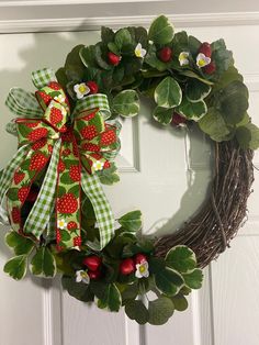 a green wreath with strawberries and flowers on the front door