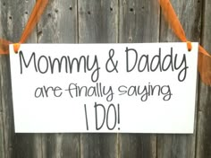 a sign that says mommy and daddy are finally saying i do hanging on a fence