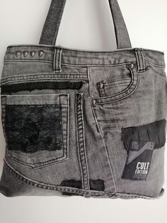 a handbag made out of grey jeans with black patches on the side and zippers at the bottom