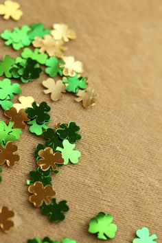 green and gold shamrocks are scattered on a brown surface