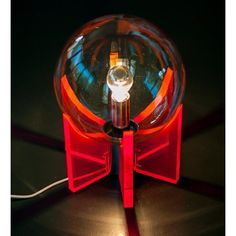 a red and black object sitting on top of a table next to a light bulb