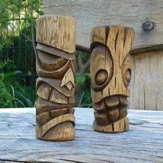 two carved wooden tiki statues sitting on top of a wooden table