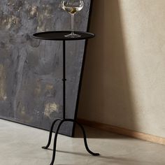 a wine glass sitting on top of a table next to a stone wall and floor