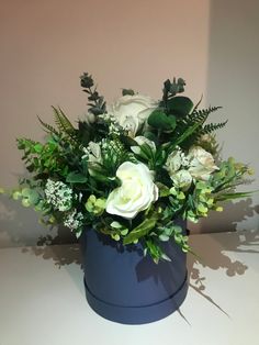 a blue vase filled with white flowers and greenery