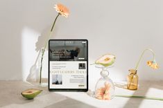 a tablet computer sitting on top of a table next to vases filled with flowers