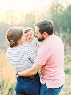 a man and woman holding a baby in their arms