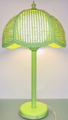 a green table lamp with a yellow shade on the base and a cord attached to it