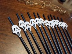 six black and white chopsticks are lined up on a wooden table with string