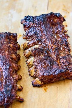 two pieces of meat sitting on top of a wooden cutting board next to each other