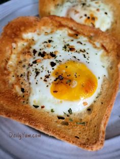 two pieces of bread with an egg in the middle on top of each other, sitting on a plate