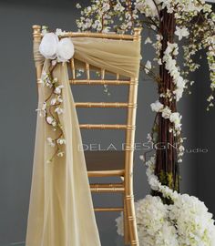 the chair is decorated with white flowers and greenery for an elegant touch to the room