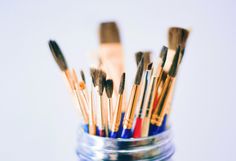 a jar filled with lots of paint brushes