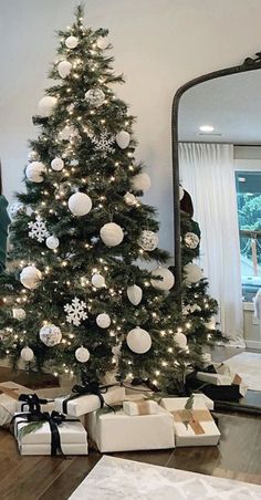 a christmas tree with white and silver ornaments is in the middle of a living room